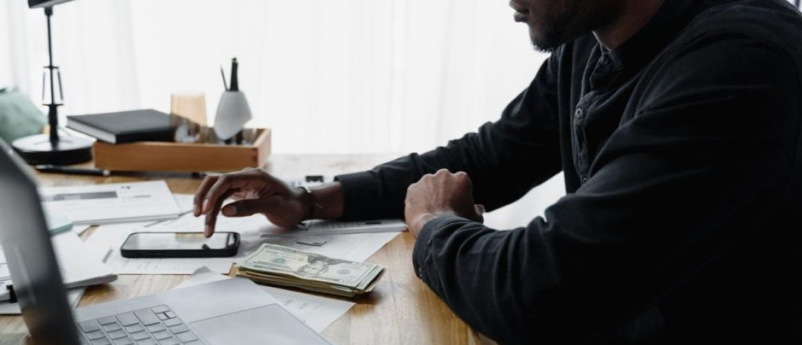 Man reviewing household bills and writing a plan at a kitchen table.