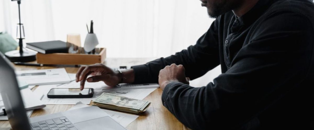 Man reviewing household bills and writing a plan at a kitchen table.