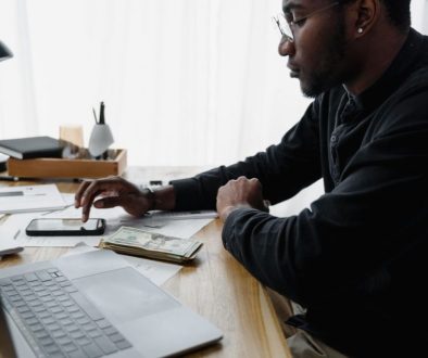 Man reviewing household bills and writing a plan at a kitchen table.