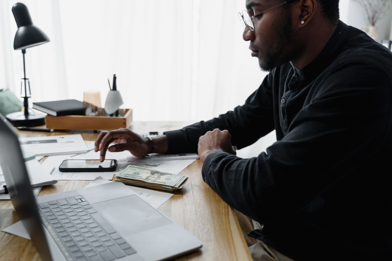 Man reviewing household bills and writing a plan at a kitchen table.